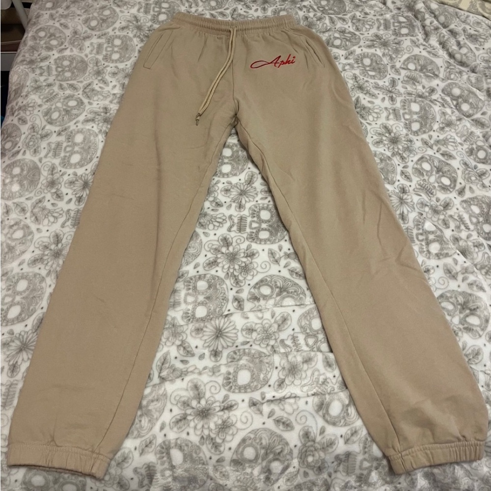 Beige Alpha Phi drawstring sweatpants w/ “Aphi” in red cursive writing & pockets